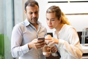 Une personne regarde son téléphone pendant que son partenaire l’observe avec insistance.